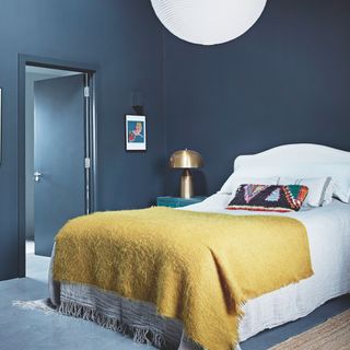 bedroom with blue wall and bedding with cushions and throw