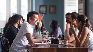 Young people sit and chat around table