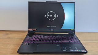 A black ASUS TUF Gaming A15 laptop on a wooden table