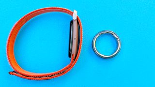 Close-up of the Fitbit Air and Oura Ring 4 Ceramic against a blue background