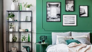 A bedroom with artwork hanging against a green wall