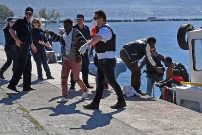 Coast guard members help migrants to disembark at the port of Kalmata in South Peloponnese, Greece, 17 April 2016.