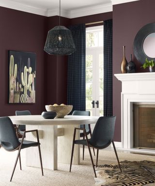 dining room with dark purple walls, oval dining table with dark gray chairs, white fireplace in the corner