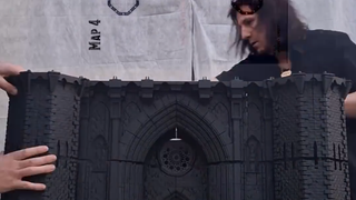 Two men assembling a 3D-printed castle model that is the size of an adult person.