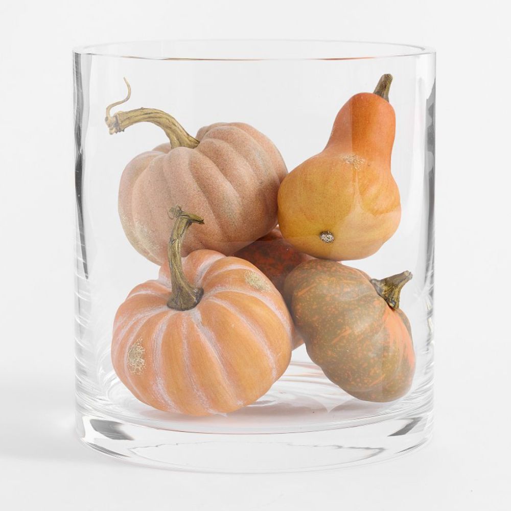 Faux orange pumpkins in a glass vase