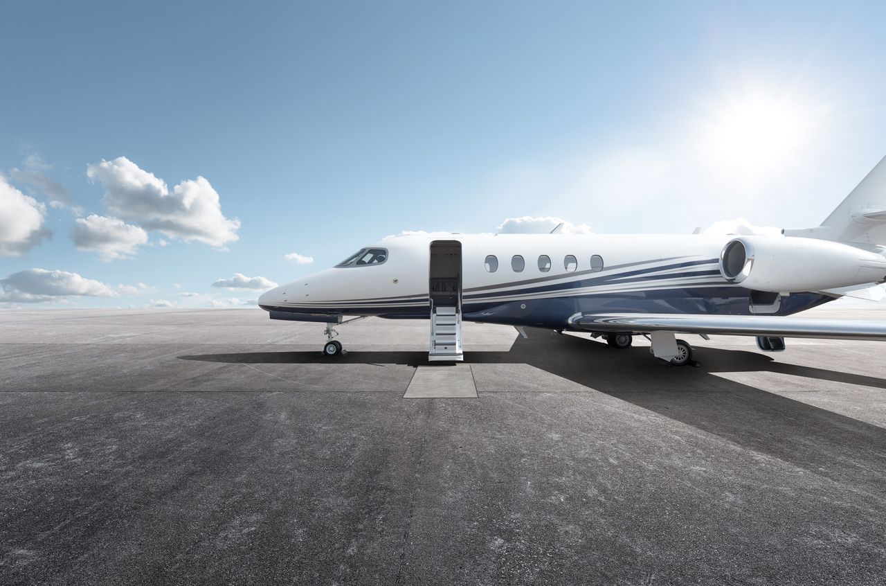 A private plane on a tarmac in the sunshine with the boarding stairs down.