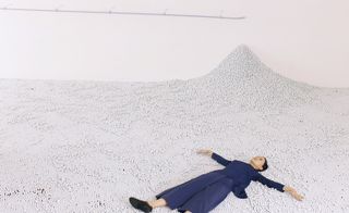 A female lying down on top of 100,000 white glass marbles.