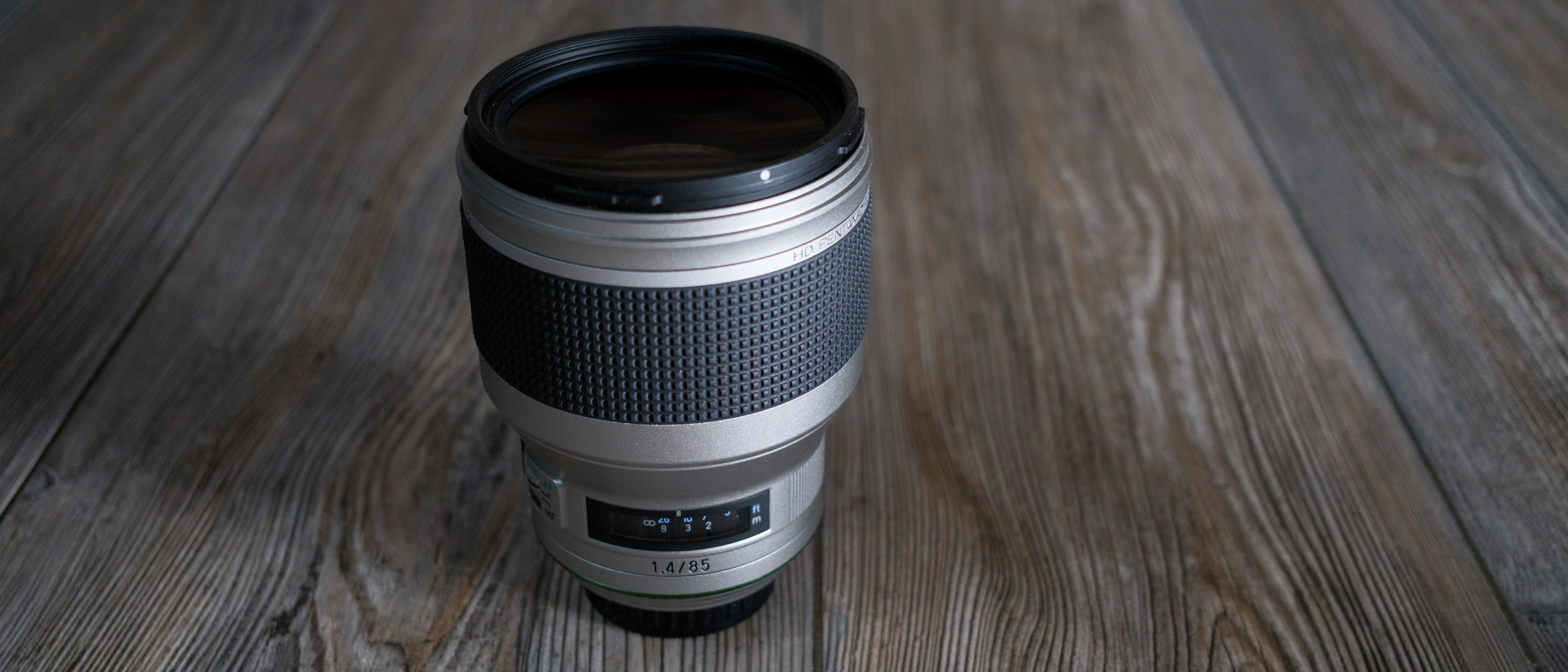 The Pentax 85mm f/1.4 SDM AW on a wood background
