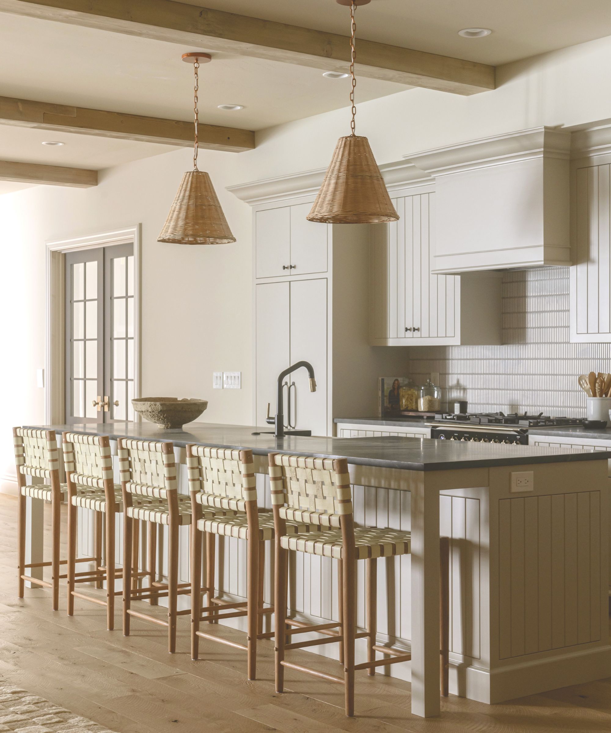 modern kitchen with all-neutral color scheme, wood ceiling beams and large island with bar chairs