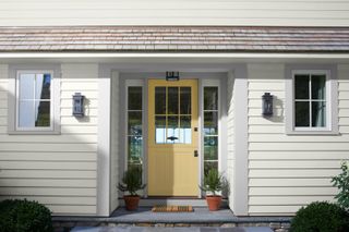 House exterior with white siding and yellow painted glazed front door