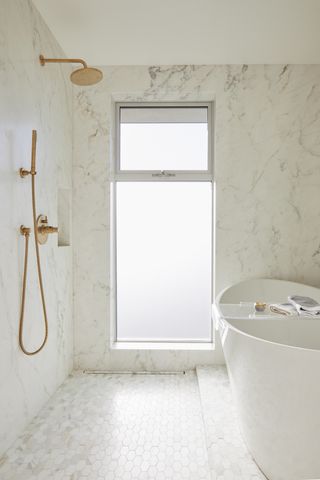 An all-white bathroom with a large bathtub and a curbless shower