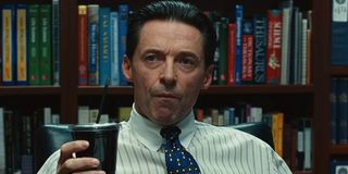 Hugh Jackman pulls a face of surprise with a drink cup in his hand in Bad Education.