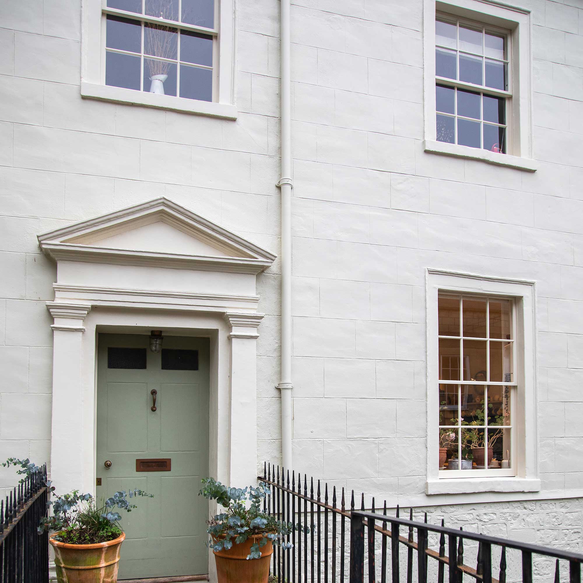 exterior of a white painted georgian villa with large sash windows and green painted door