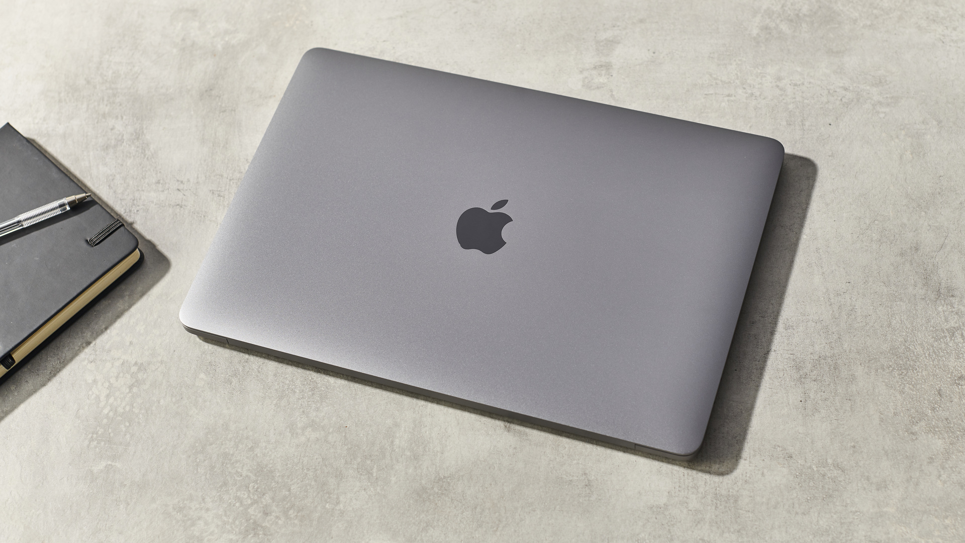 Apple MacBook Pro 13-inch (M1, 2020) on a desk next to a notebook