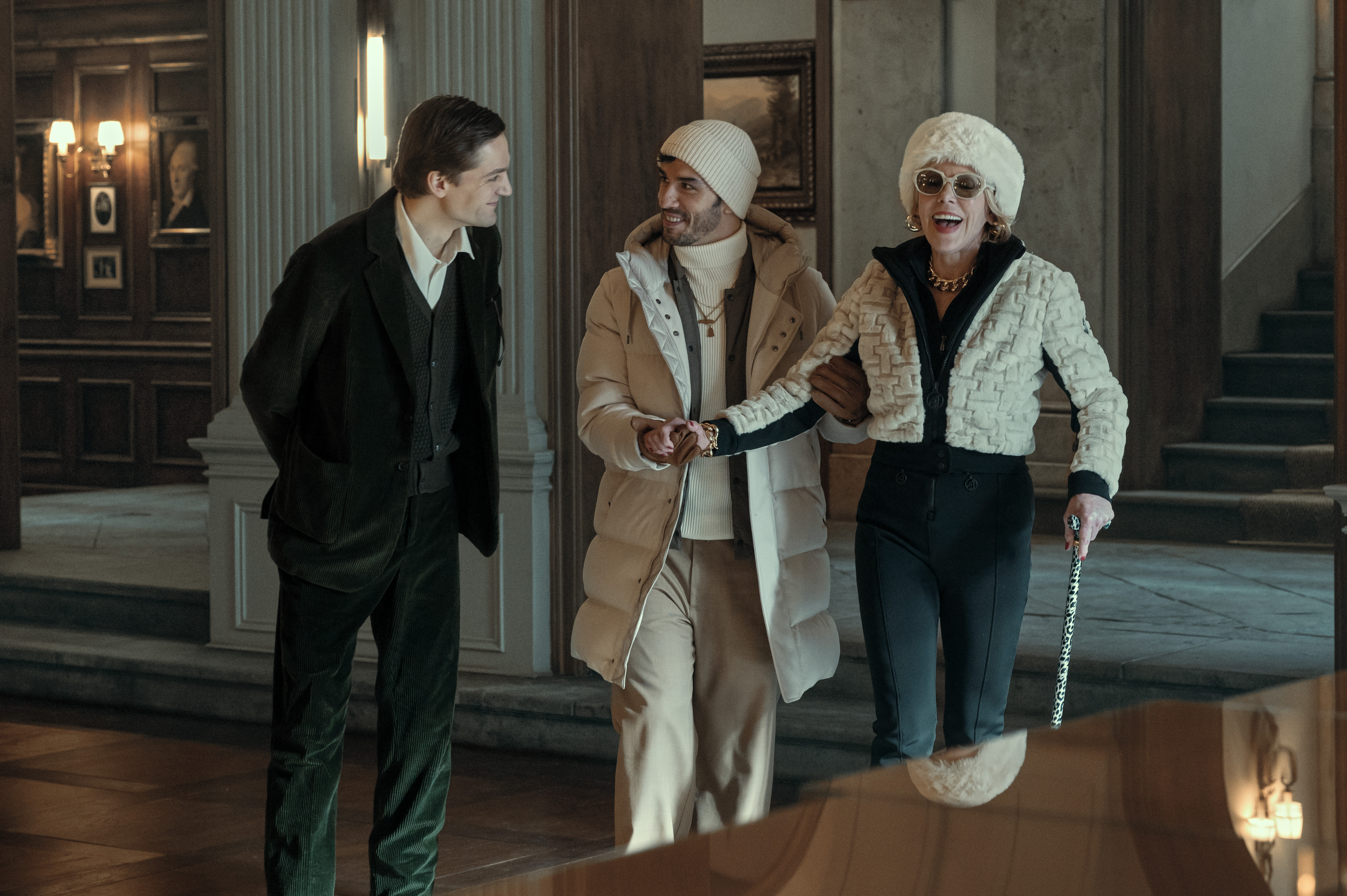 LUCAS ENGLANDER, ARAS AYDIN, CHRISTINE BARANSKI walking through a hallway wearing a suit and winter weather clothing in nine perfect strangers season 2