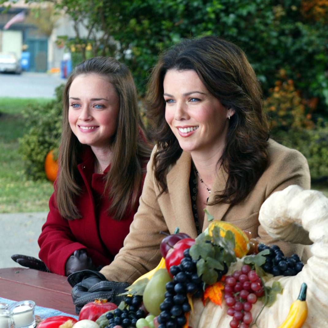 Rory and Lorelai Gilmore sitting at a picnic table in winter coats