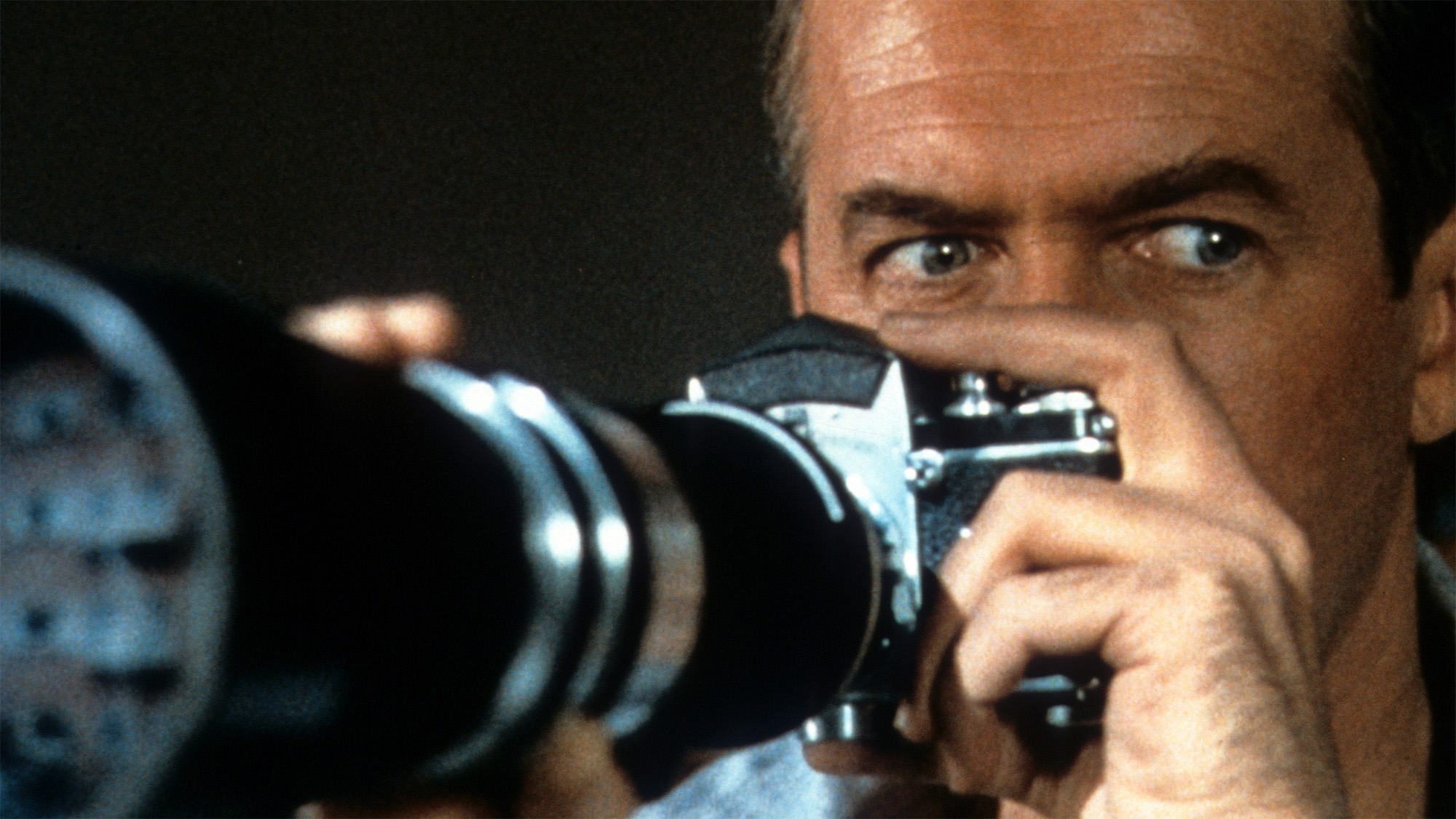 James Stewart looks through his camera in a scene form the film 'Rear Window', 1954