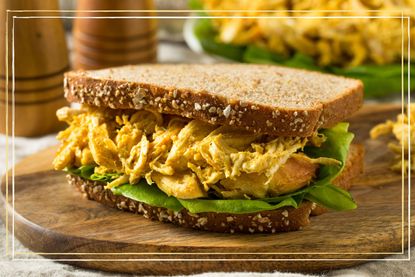 a close up of a Coronation chicken sandwich on a wooden chopping board