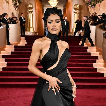 a black woman with short hair posing on a red carpet wearing a black gown