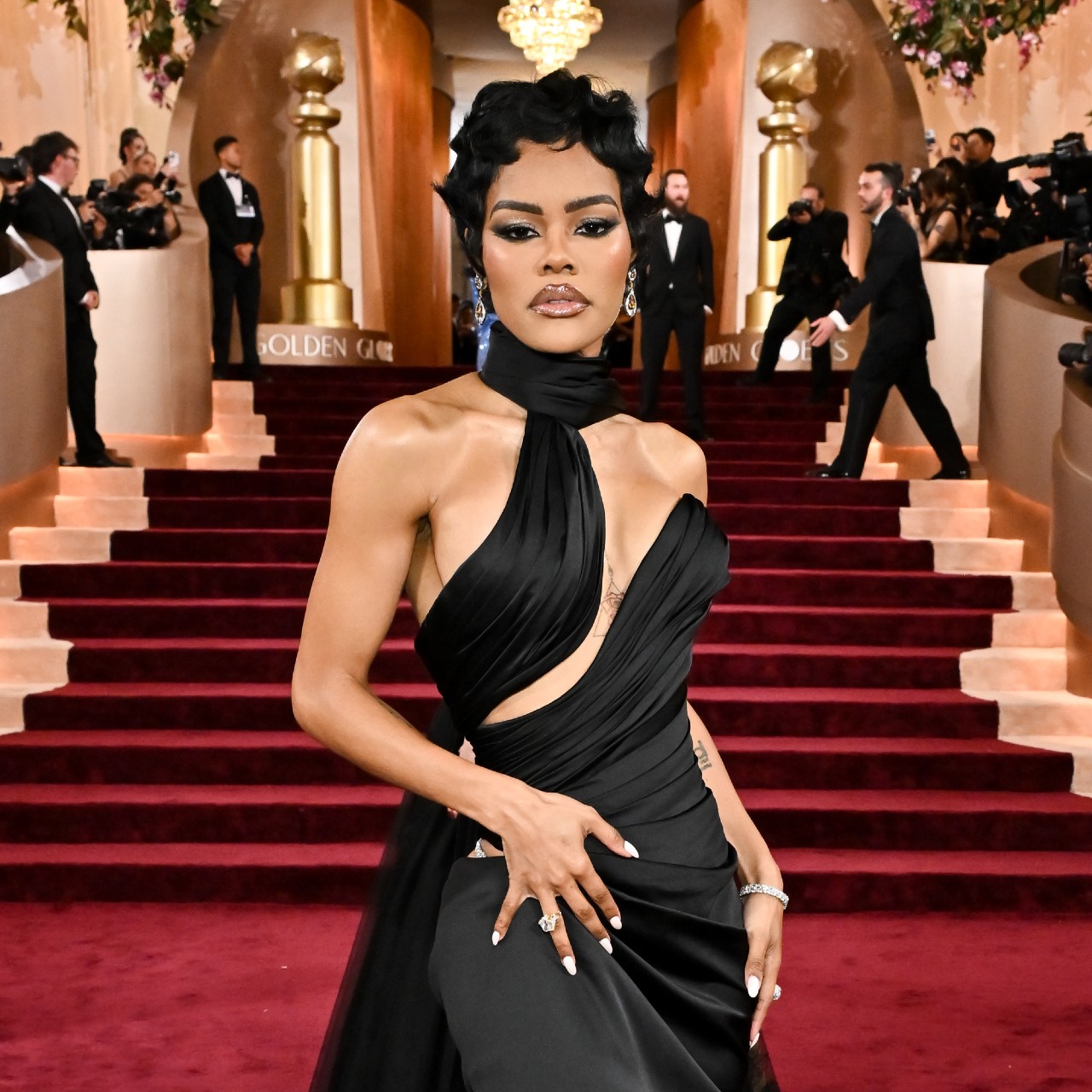 a black woman with short hair posing on a red carpet wearing a black gown