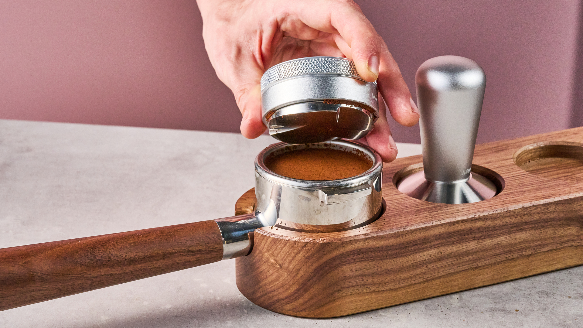 A man removes the Meraki Espresso Machine's coffee distributor to show the evenly spread grounds inside the portafilter.