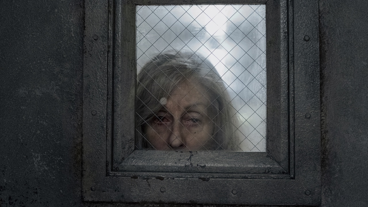 Red-eyed Dorry looking through the silver door's window in The Terror: Devil in Silver