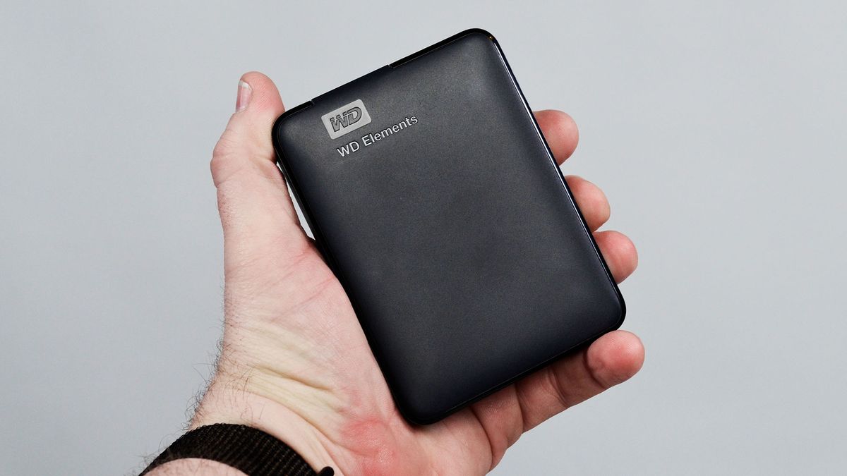 A msculine hand holding a WD Elements external hard drive