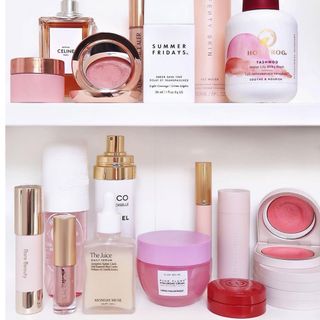 Color-coordinated beauty products in pinks on white, tiered open shelving