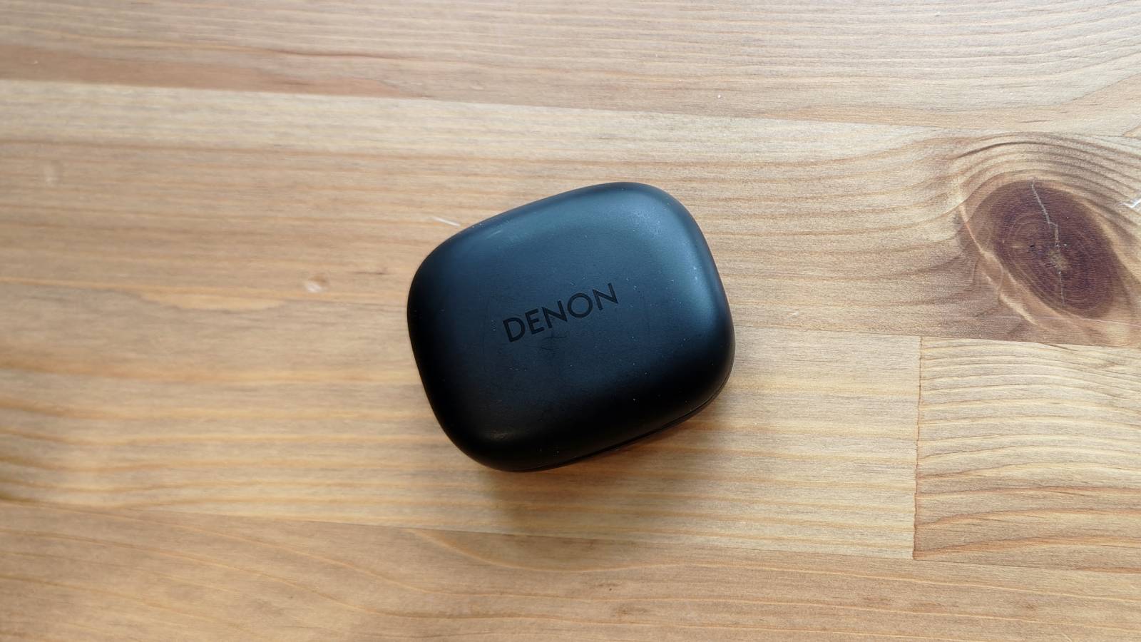The Denon AH-C840NCW against a wooden table.
