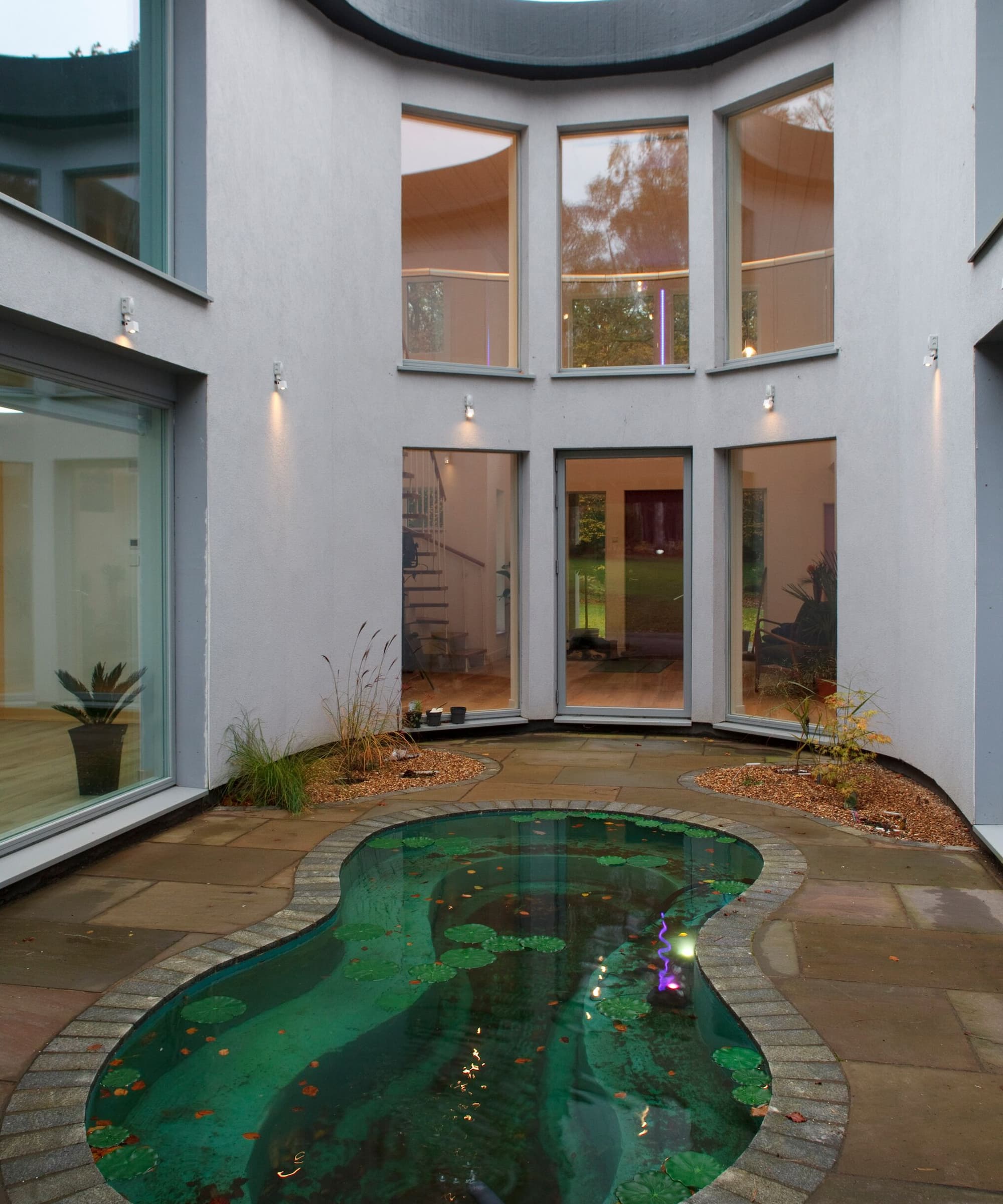 An outside small pool surrounded by a white curved house