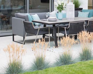 Tufts of ornamental grasses lining the edge of a patio area
