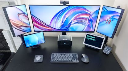 A triple monitor setup with an Amazon and a Google smart display underneath it on a desk