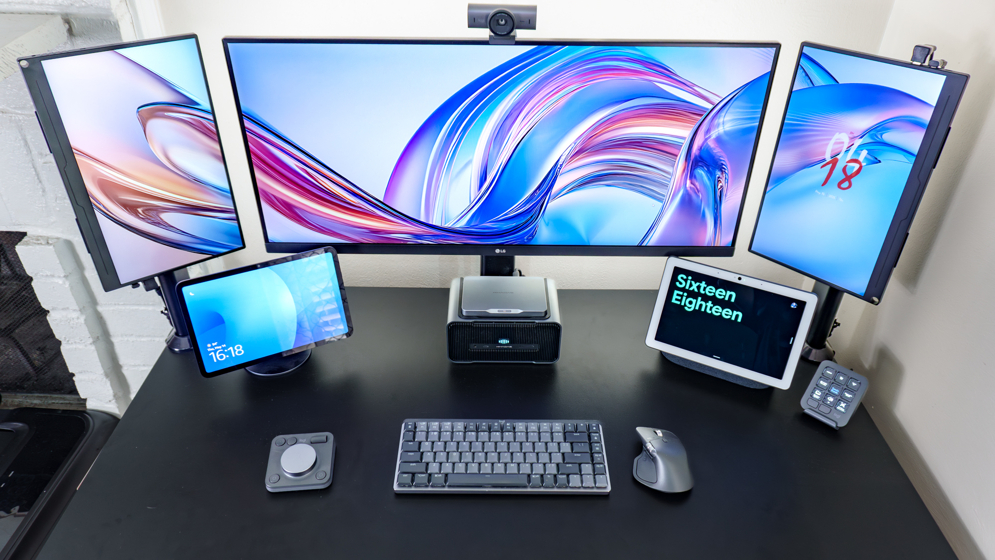 A triple monitor setup with an Amazon and a Google smart display underneath it on a desk