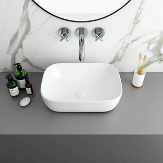 white rectangular bathroom basin with marble wall tiles and grey worktop