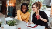 two women at laptops smiling