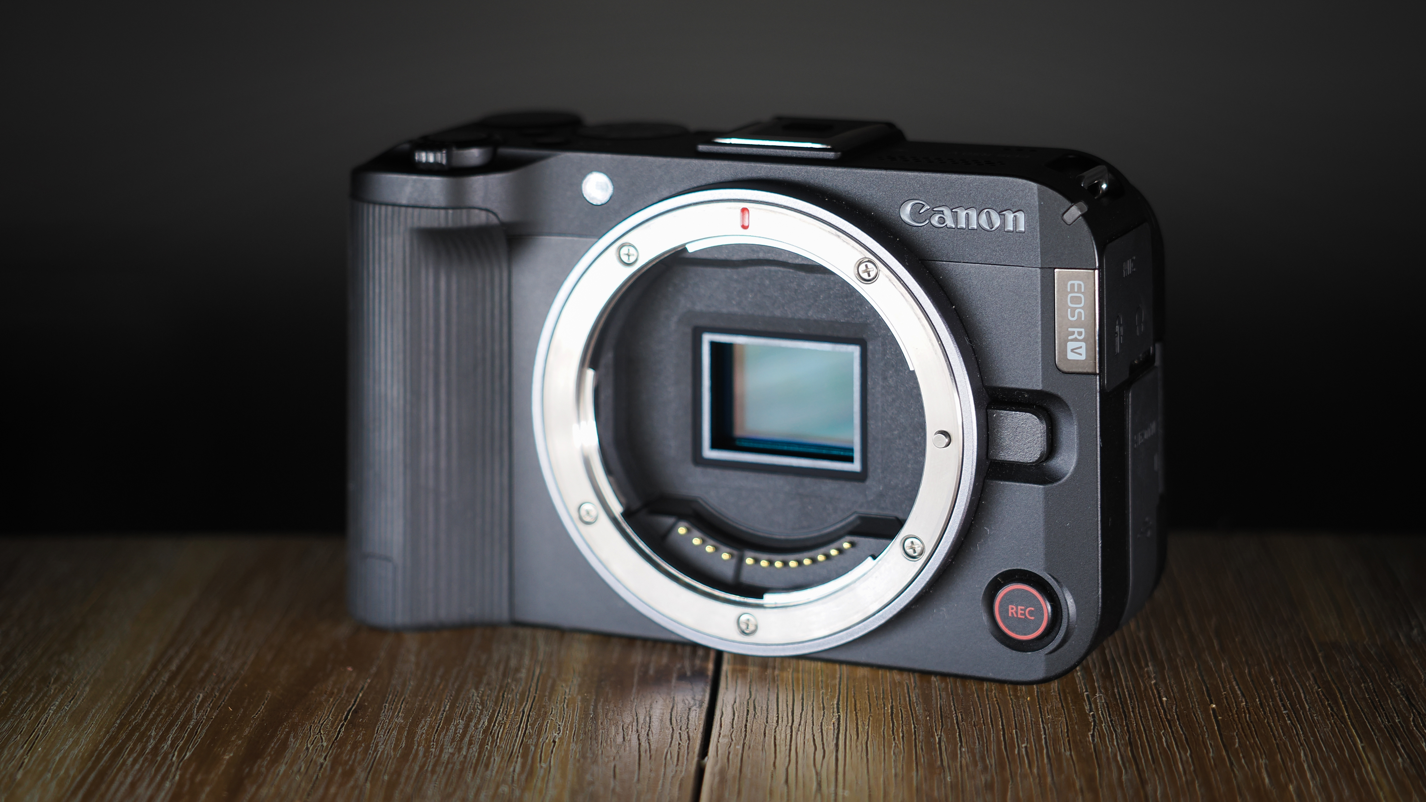 Canon EOS R50 V on a wooden surface, against a dark background