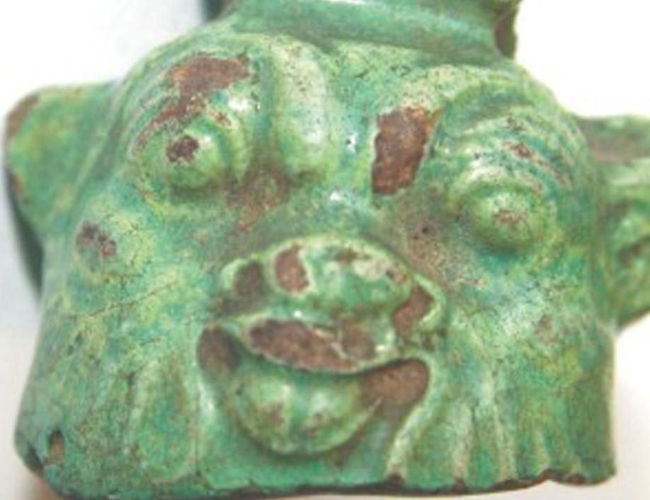 A bell depicting the dwarf god Bes.