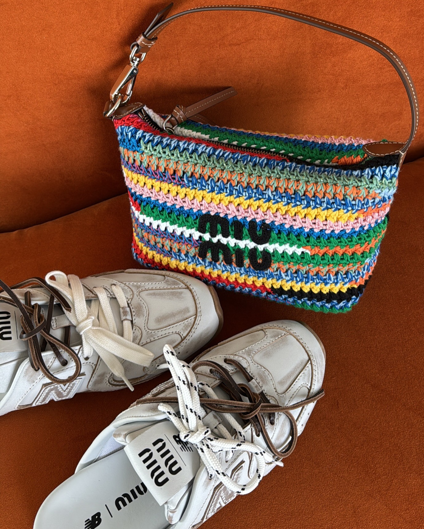 Image of Miu Miu backless trainers next to Miu Miu multicoloured woven bag.