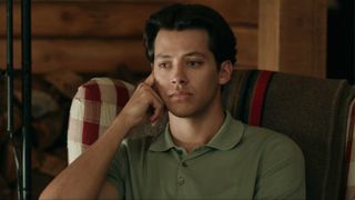 Sam sitting with his left hand on his face looking very, very sad. 