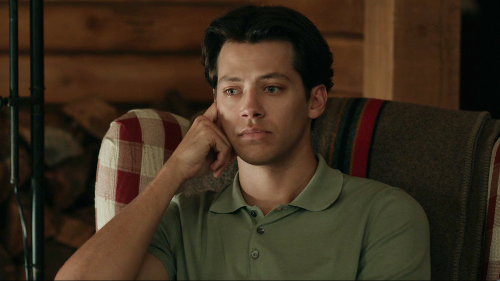 Sam sitting with his left hand on his face looking very, very sad. 
