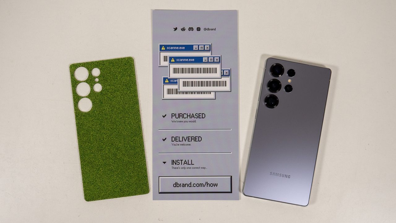 The Touch Grass DBrand skin alongside the install instruction card and a Samsung Galaxy S25 Ultra