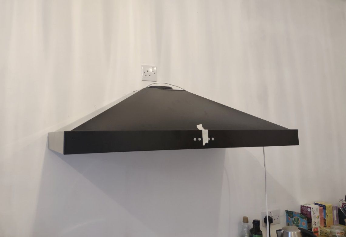 A black cooker hood being fitted on a white kitchen wall