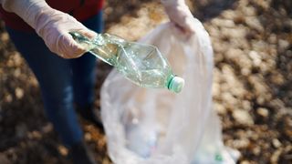 Woman picking up trash in forest