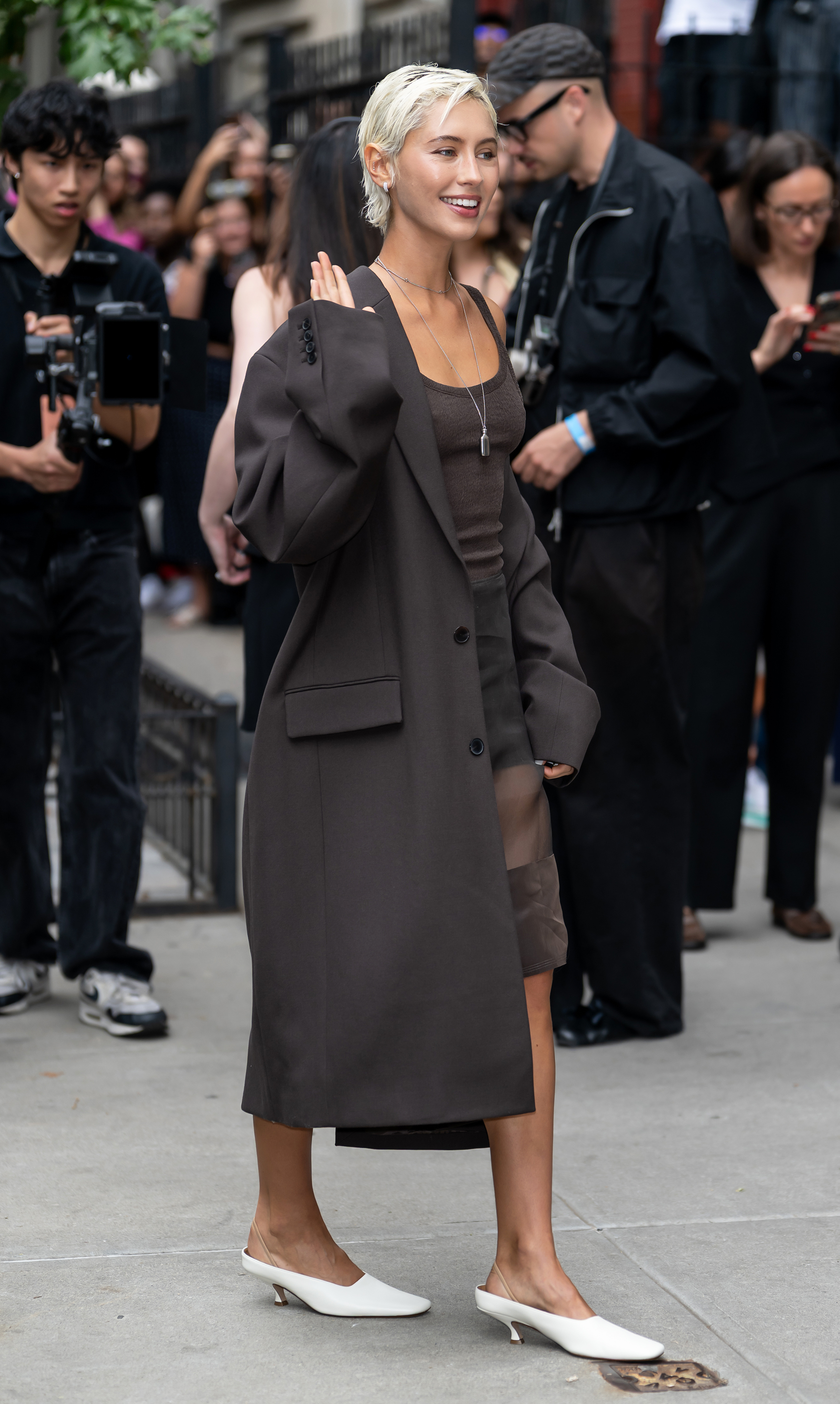 Iris Law walks to a fashion show wearing an all-brown outfit and cream mid-heel pumps.
