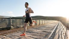 full-length portrait of runner sprinting on a bridge