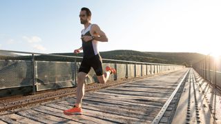 full-length portrait of runner sprinting on a bridge