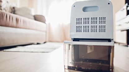 A small white dehumidifier open on a living room floor