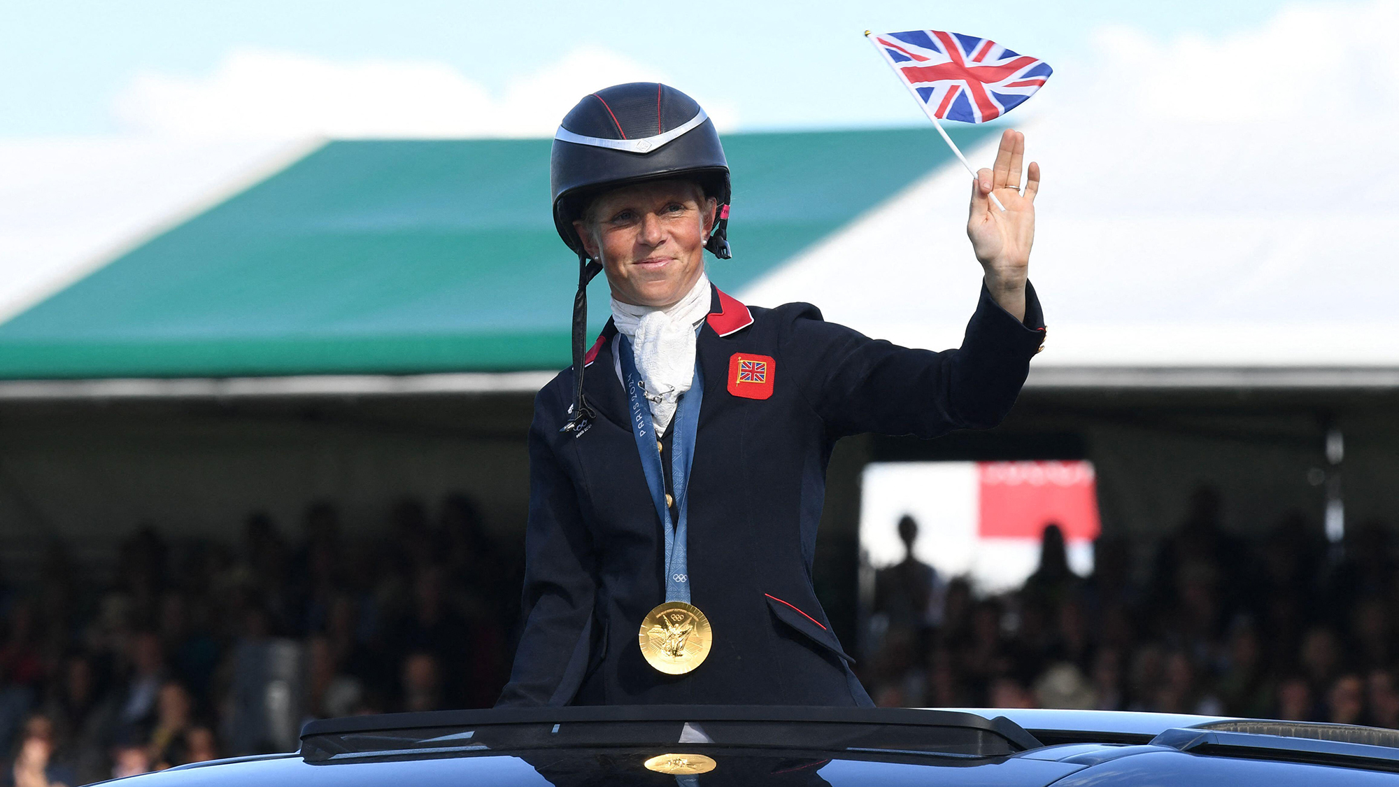 Ros Canter waves a small union flag as is driven around the Burghley main arena