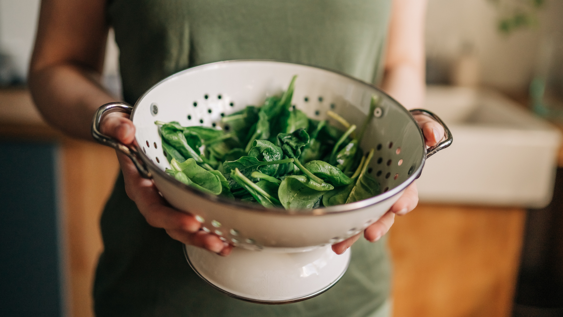 woman holder a colander of washed spinach
