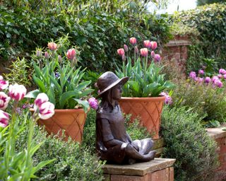 tulips planted in a garden border around a bronze statue